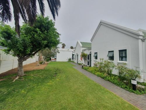 a white house with a tree and a grass yard at Langholm Hotel in Walvis Bay