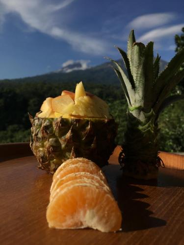 a cut up pineapple and a piece of bread on a table at Rinjani Houseboon in Senaru