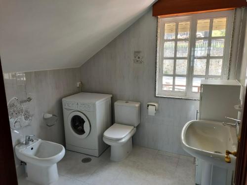 a bathroom with a toilet sink and a washing machine at Apartamento Loft A Estivada in Rosal
