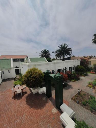 a park with benches and a building with palm trees at Langholm Hotel in Walvis Bay