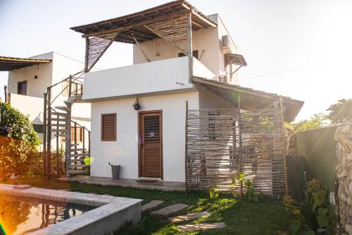 a white house with a fence in the yard at Zero Meia Um Pousada in São Miguel do Gostoso