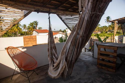 a hammock on the balcony of a house at Zero Meia Um Pousada in São Miguel do Gostoso