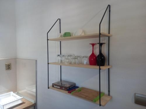 une étagère avec des vases et des verres sur un mur dans l'établissement Apartment Karmen, à Sumartin