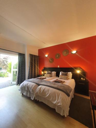 a bedroom with a large bed with a red wall at Langholm Hotel in Walvis Bay
