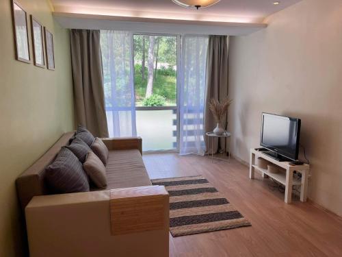 a living room with a couch and a flat screen tv at Apartamentai Forest green in Nida