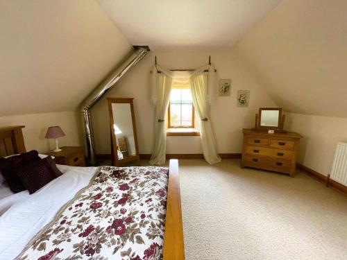 a bedroom with a large bed and a window at Deveron Valley Cottages in Marnoch