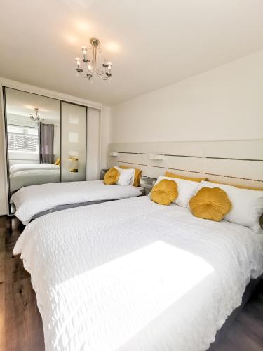two beds in a room with white sheets and yellow pillows at Bee At Home in Cefn-coed-y-cymmer