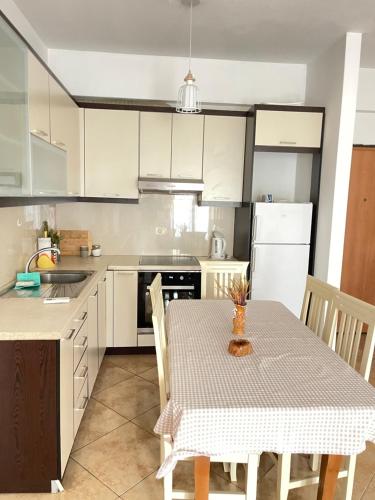 kuchnia ze stołem i kuchnia z białymi szafkami w obiekcie Vlore apartament 1 we Wlorze