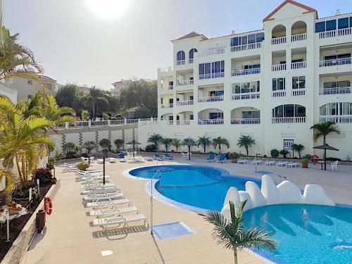 a hotel with a swimming pool and chairs and a building at Ocean Golf & Country Club J&K in San Miguel de Abona