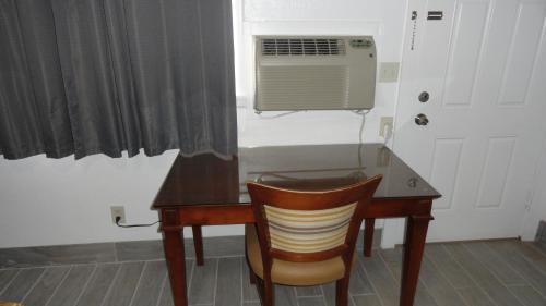 a desk with a chair and a window with a fan at ECONOMY INN in Brownfield