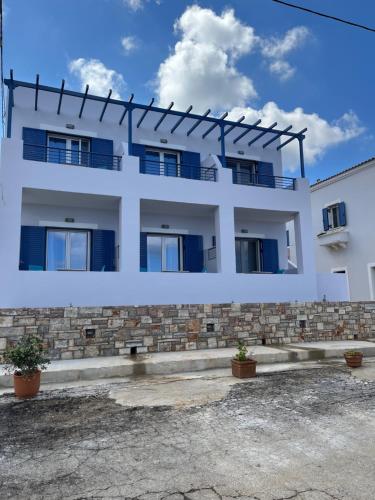 a white building with blue windows at Anesis Hotel in Agia Pelagia Kythira