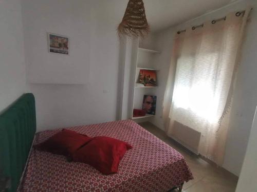 - une chambre avec un lit doté d'une couverture rouge et d'une fenêtre dans l'établissement Appartement 2 à Carthage byrsa, à Douar ech Chott