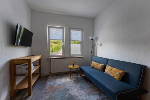 a living room with a blue couch and a television at Ferienwohnung am Steinbach 1 in Thale