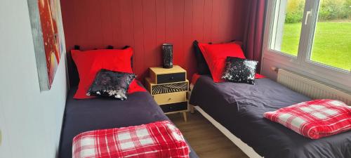 two twin beds in a room with red walls at Villa repos in Neuilly-lʼHôpital