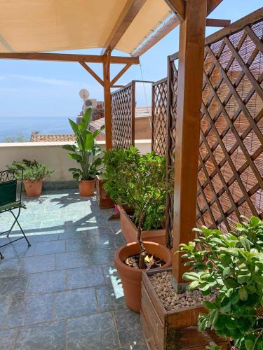 a patio with potted plants and a wooden pergola at Guest house Le Sibille in Taormina