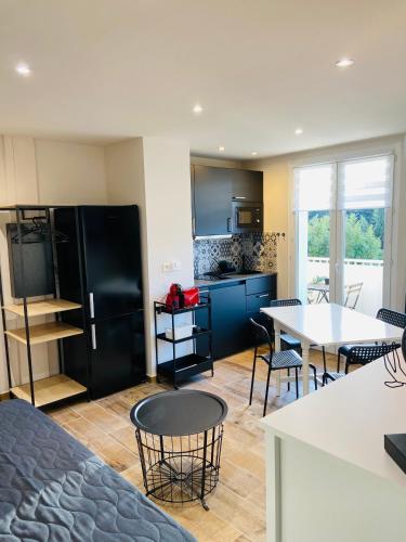 Il comprend une cuisine équipée d'un réfrigérateur noir, de tables et de chaises. dans l'établissement CASA MARGOT T2 Plage 500m, à La Seyne-sur-Mer