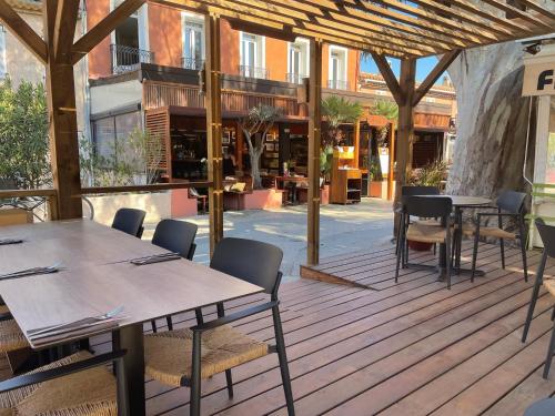 een patio met tafels en stoelen op een houten terras bij L'Oustaou De Porquerolles in Porquerolles