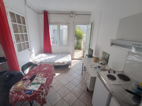 a small room with a kitchen with a table and a bed at Chambre meublée indépendante, avec piscine et jardin, 1 lit pour 2 personnes in Toulouse