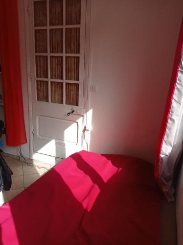 a bedroom with a red bed and a door at Studio indépendant, avec piscine et jardin, direct gare aéroport, 1 lit pour 2 personnes Direct Gare Aéroport in Toulouse