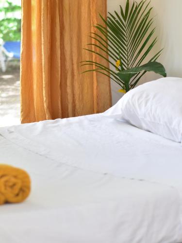 ein weißes Bett mit einem Kissen und einer Pflanze in der Unterkunft Guesthouse Congo Tempisque in Liberia