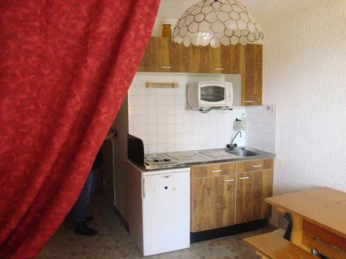 a small kitchen with a red curtain in a room at Studio au calme face aux montagnes dans station de ski in La Morte