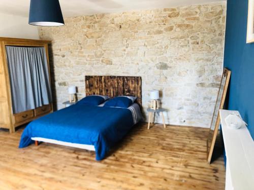a bedroom with a blue bed and a stone wall at La Plooz in Plozévet