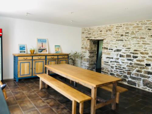 Cette chambre dispose d'une table en bois et d'un mur en pierre. dans l'établissement La Plooz, à Plozévet