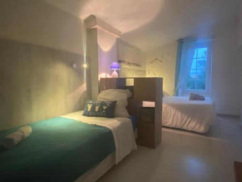 een kleine slaapkamer met 2 bedden en een raam bij Logis des Lauriers Roses in Marennes