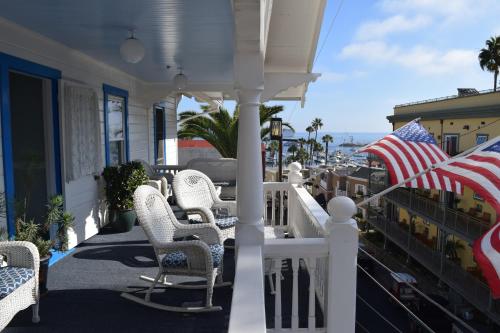 a porch with white chairs and an american flag at Hotel Catalina in Avalon