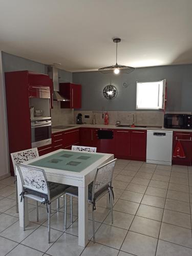 una cocina con armarios rojos y una mesa y sillas blancas. en Joss Nath homes, en Melun