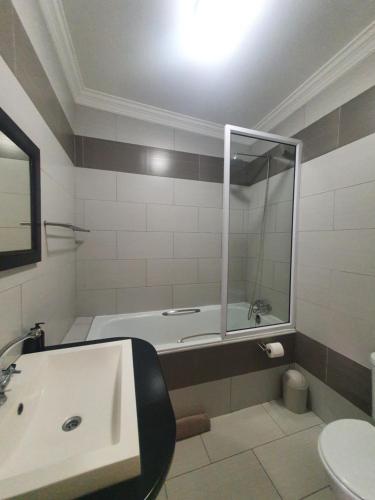 a bathroom with a tub and a sink with a mirror at Langholm Hotel in Walvis Bay