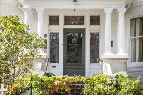 a white house with a green door and columns at Ryan Mansion in St. John's