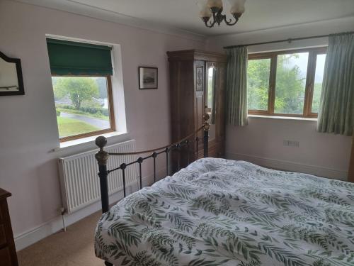 ein Schlafzimmer mit einem Bett und zwei Fenstern in der Unterkunft Criccieth Family holiday house in Tremadoc