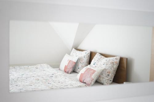 a white room with a bed with pillows at Apartman Sveti Rok in Požega