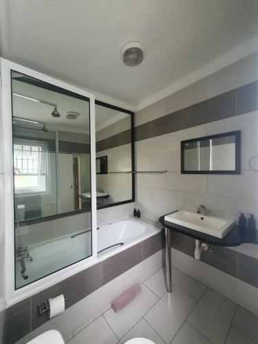 a bathroom with a tub and a sink and a mirror at Langholm Hotel in Walvis Bay
