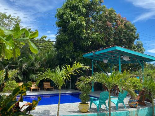 a pool with chairs and a pavilion with trees at Hotel Diversion Tropical in Brasilito
