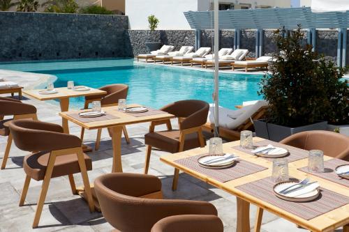 a restaurant with tables and chairs next to a pool at Amara Suites Santorini in Kamari