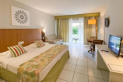 een hotelkamer met een bed, een bureau en een televisie bij Búzios Beach Resort in Búzios