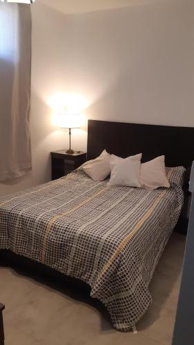 a bedroom with a bed with a black and white comforter at Monoambiente Belgrano in La Banda
