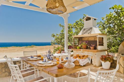 a table and chairs on a patio with the beach in the background at ViLLA SYMONE in Afiartis