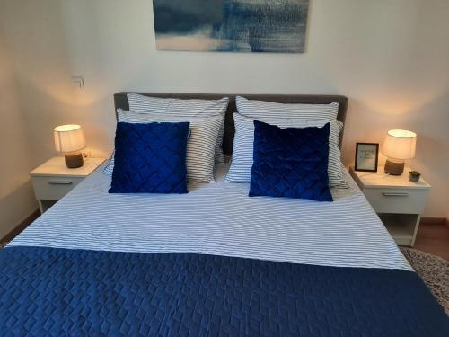 niebieskie łóżko z 2 niebieskimi poduszkami i 2 lampami w obiekcie NewTown Apartment w mieście Novigrad
