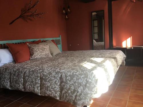 a bedroom with a bed with a gray and white comforter at El Balcón de Sotero y María in Prádena de Atienza