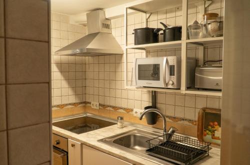 a kitchen with a sink and a microwave at El Balcón de Sotero y María in Prádena de Atienza
