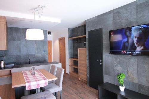 een keuken met een tafel en een tv aan de muur bij CASA IBEX - Piscina - Sauna - Baby Club in Cavalese