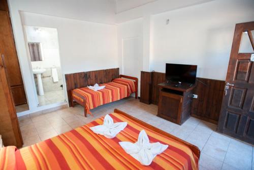 um quarto de hotel com duas camas e uma televisão em LOS HELECHOS II em Puerto Iguazú
