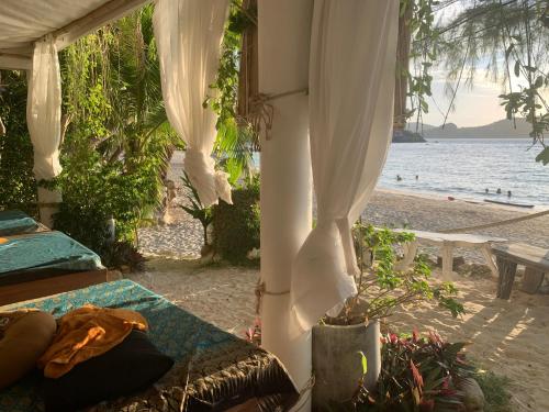 a room with a bed and a view of the beach at Coconut Beach Bungalows in Chaloklum