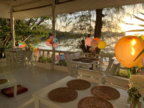 a porch with a table and balloons and a view of the water at Coconut Beach Bungalows in Chaloklum
