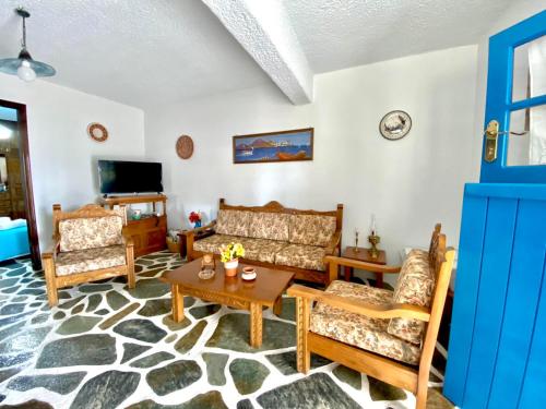 a living room with couches and a table and a tv at Gaia home in Prodromos Paros