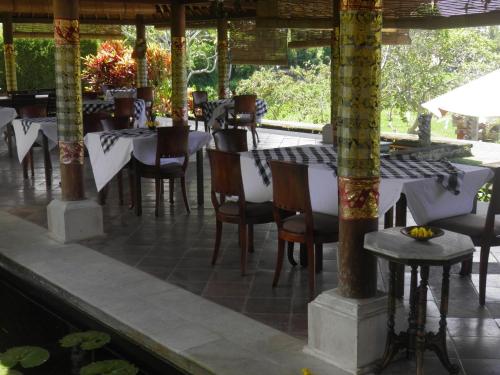 a restaurant with tables and chairs in a pavilion at Bumi Ubud Resort in Ubud