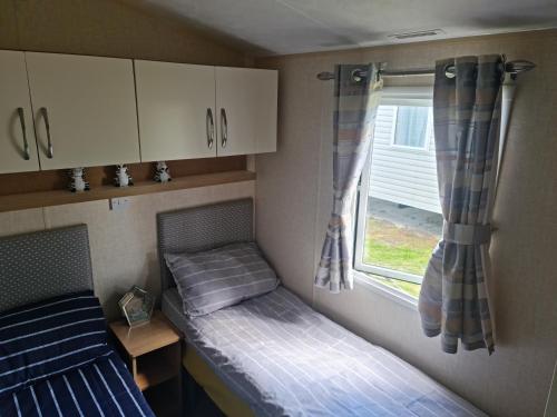 una piccola camera con due letti e una finestra di Avonmore Martello Beach a Clacton-on-Sea